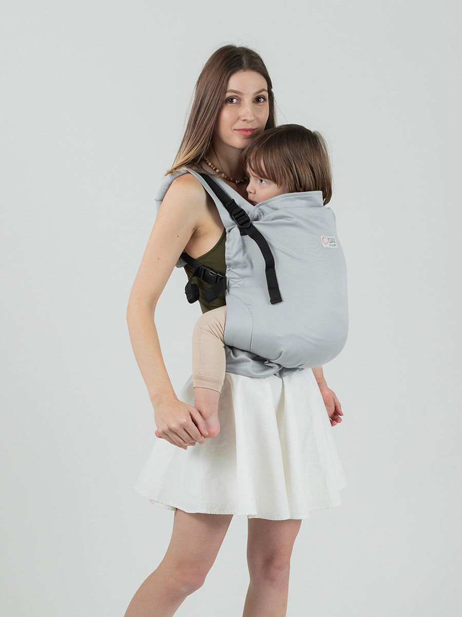 Isara Preschooler - Pearl Grey baby carrier shown with a child, featuring adjustable straps and a soft cotton design | Babymaxi