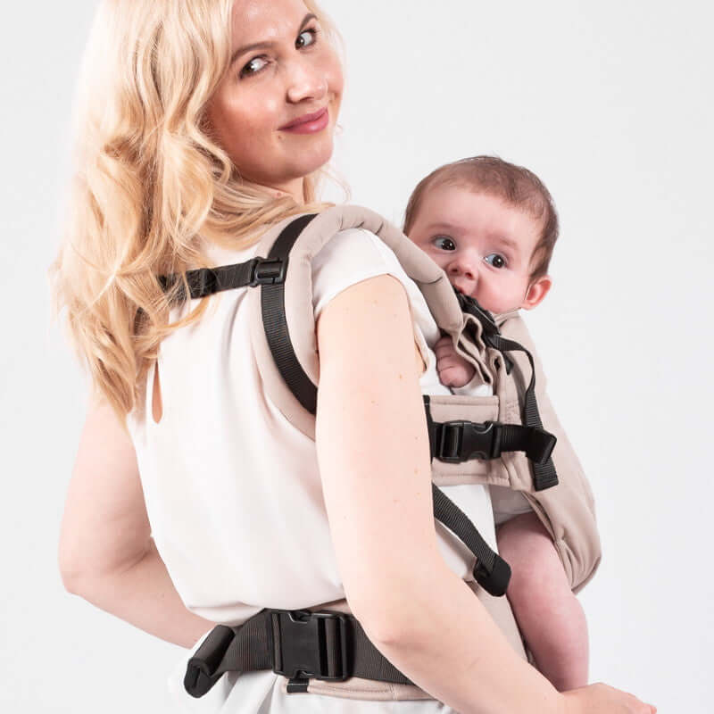 Isara The One - Caffe Latte baby carrier worn by a mother holding her baby, showcasing ergonomic design and comfort | Babymaxi