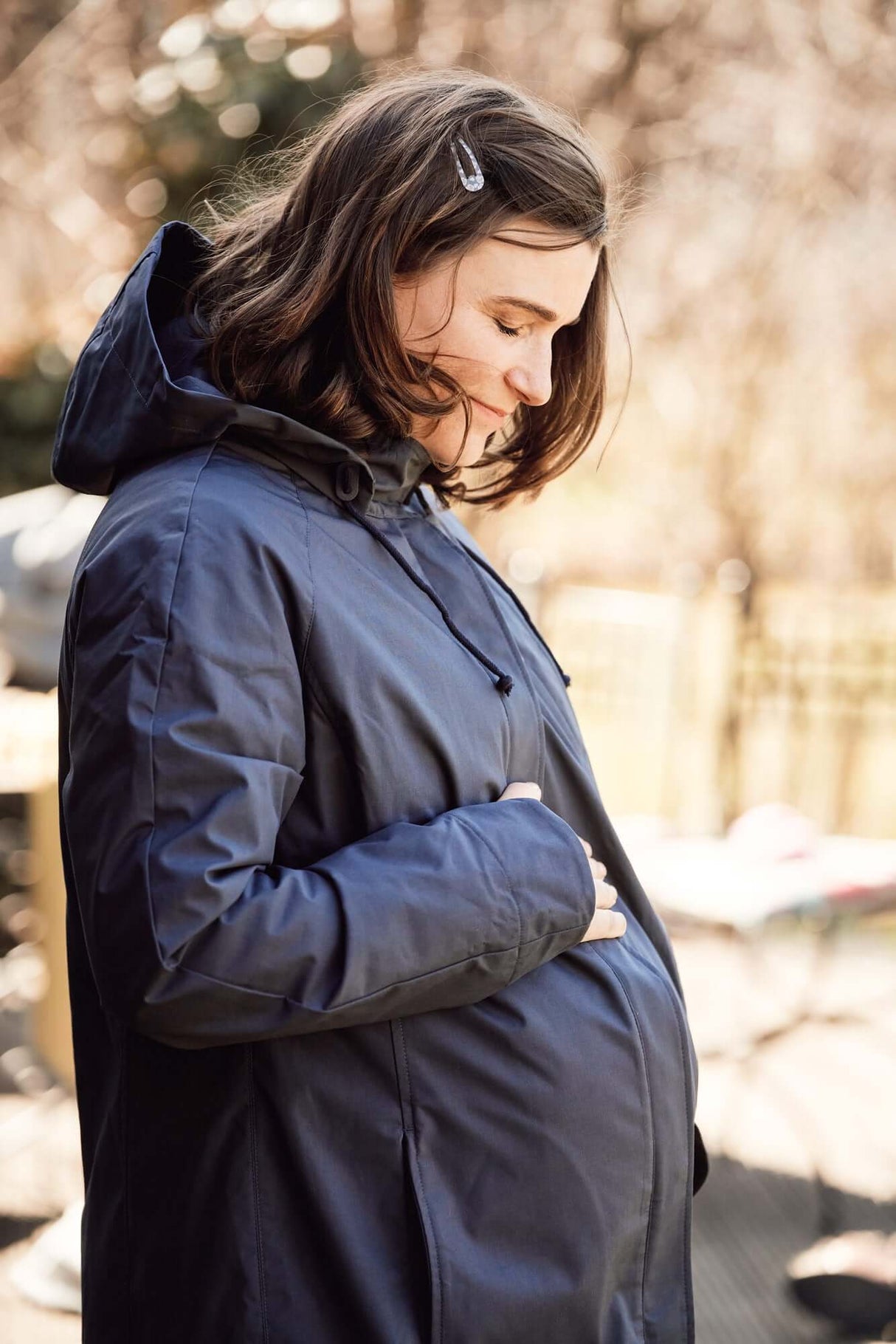 Mamalila Berlin All Season Babywearing Coat – Navy being worn by an expectant mother outdoors | Babymaxi