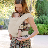 A mother lovingly carries her sleeping baby in the Ergobaby Embrace, Cosy Carrier - Cream, featuring ergonomic design | Babymaxi