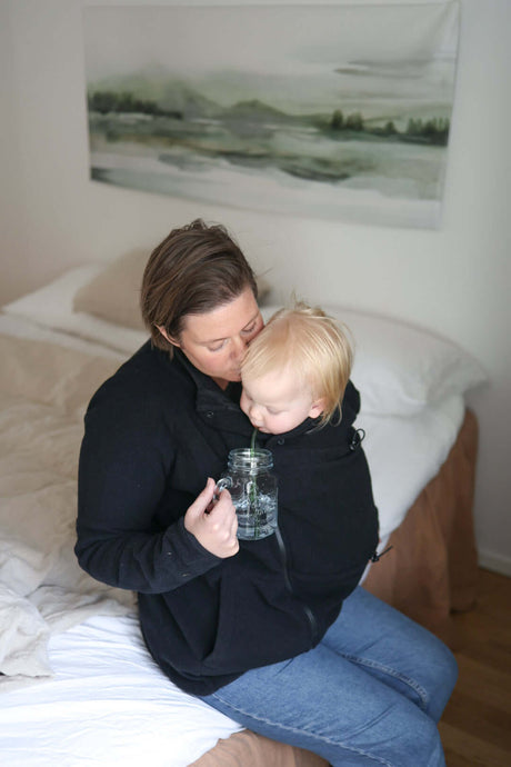 Mamalila Basel Baby Carrier Fleece Jacket – Black in use with cozy baby, perfect for cold weather walks | Babymaxi