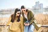 Mamalila Dublin Babywearing Coat – Mustard worn by two women enjoying a sunny day by the water | Babymaxi