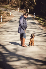 Woman wearing Mamalila Dublin Babywearing Coat – Navy walking her dog on a sunny path | Babymaxi