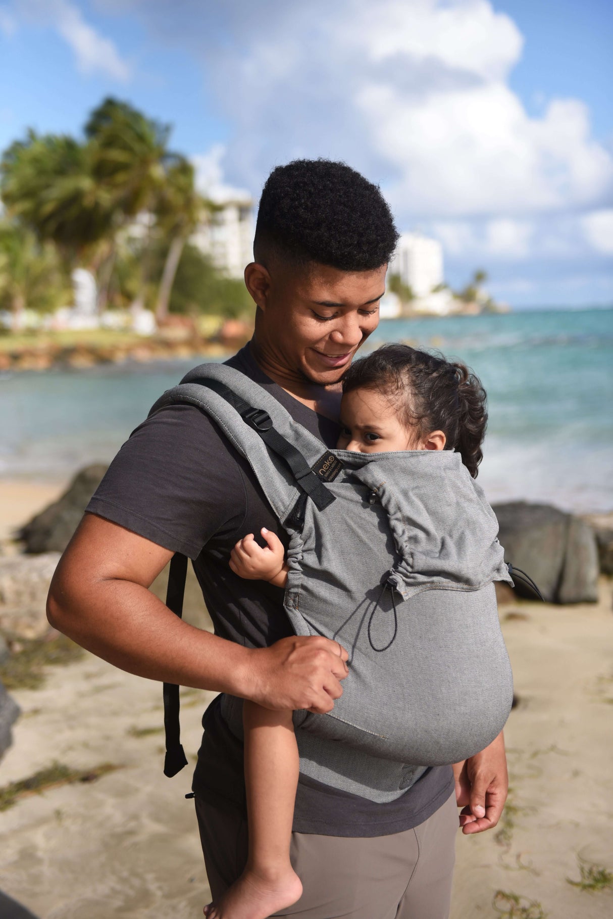 Parent carrying child in Neko Switch Toddler Carrier - Bold at beach, showcasing ergonomic design and comfort for adventures | Babymaxi