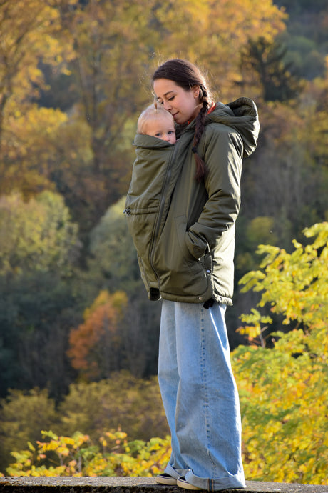 Mamalila Boston Babywearing Jacket Olive, mom wearing baby in carrier jacket on an autumn walk