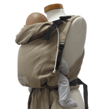 Close-up of Storchenwiege Talemo Half-Buckle Baby Carrier - Sand securely holding a baby, showcasing its adjustable buckles and wrap straps. | Babymaxi