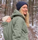 Mamalila Allrounder Winter softshell babywearing jacket in agave green, mum carrying her baby on her back on a snowy walk